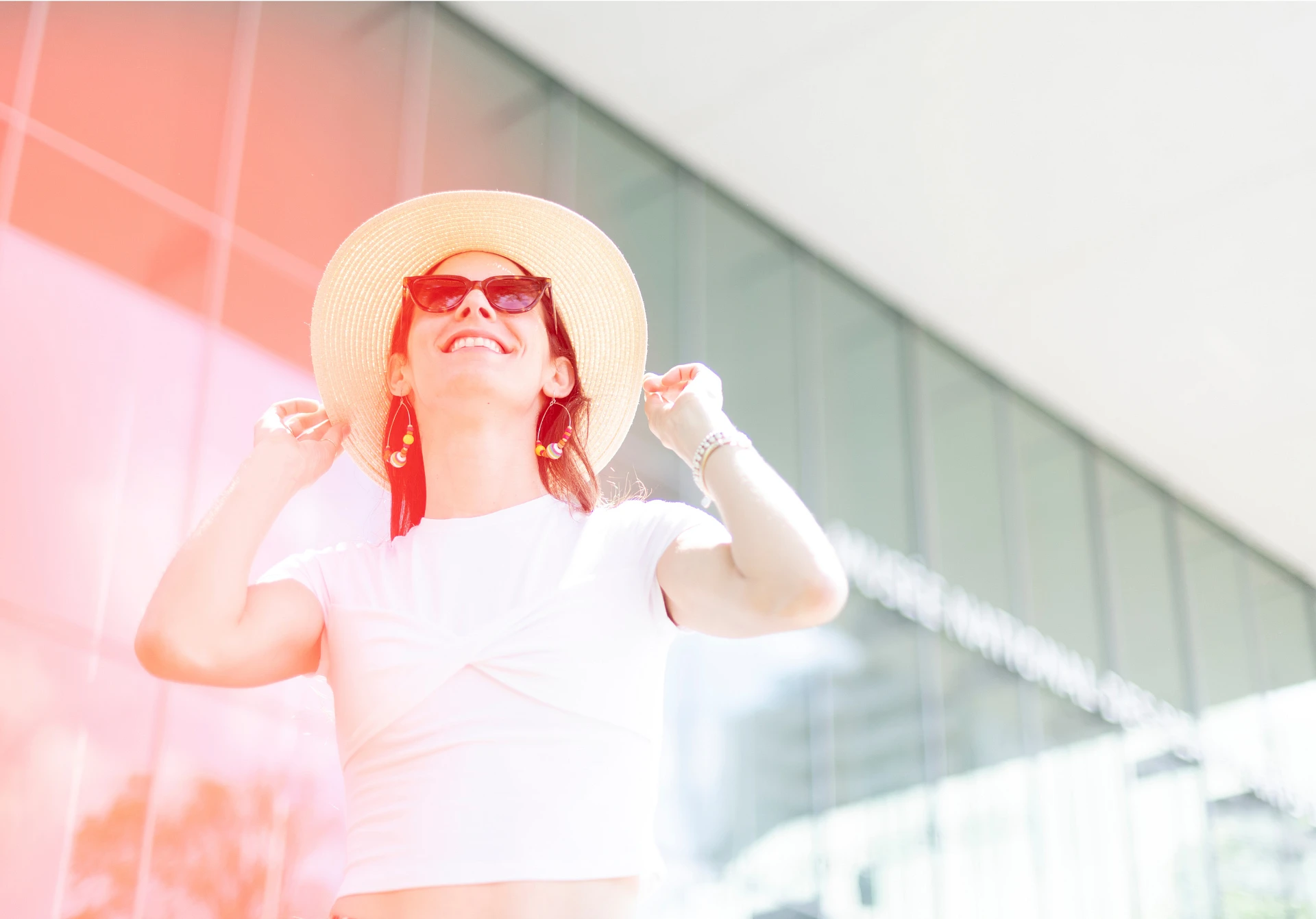 Une visiteuse portant un chapeau et des lunettes de soleil devant le pavillon Pierre Lassonde
