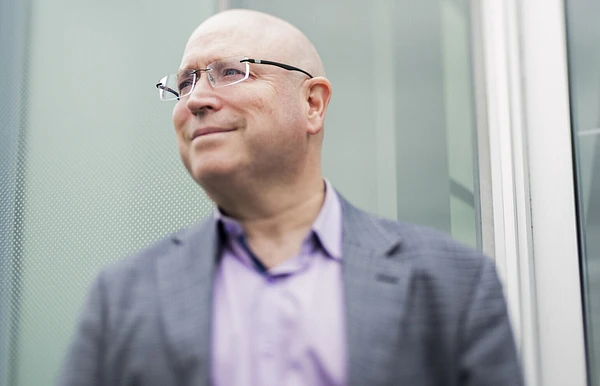François Rochon, administrateur du Musée national des beaux-arts du Québec, photographié à l'extérieur du Musée, devant un mur vitré.