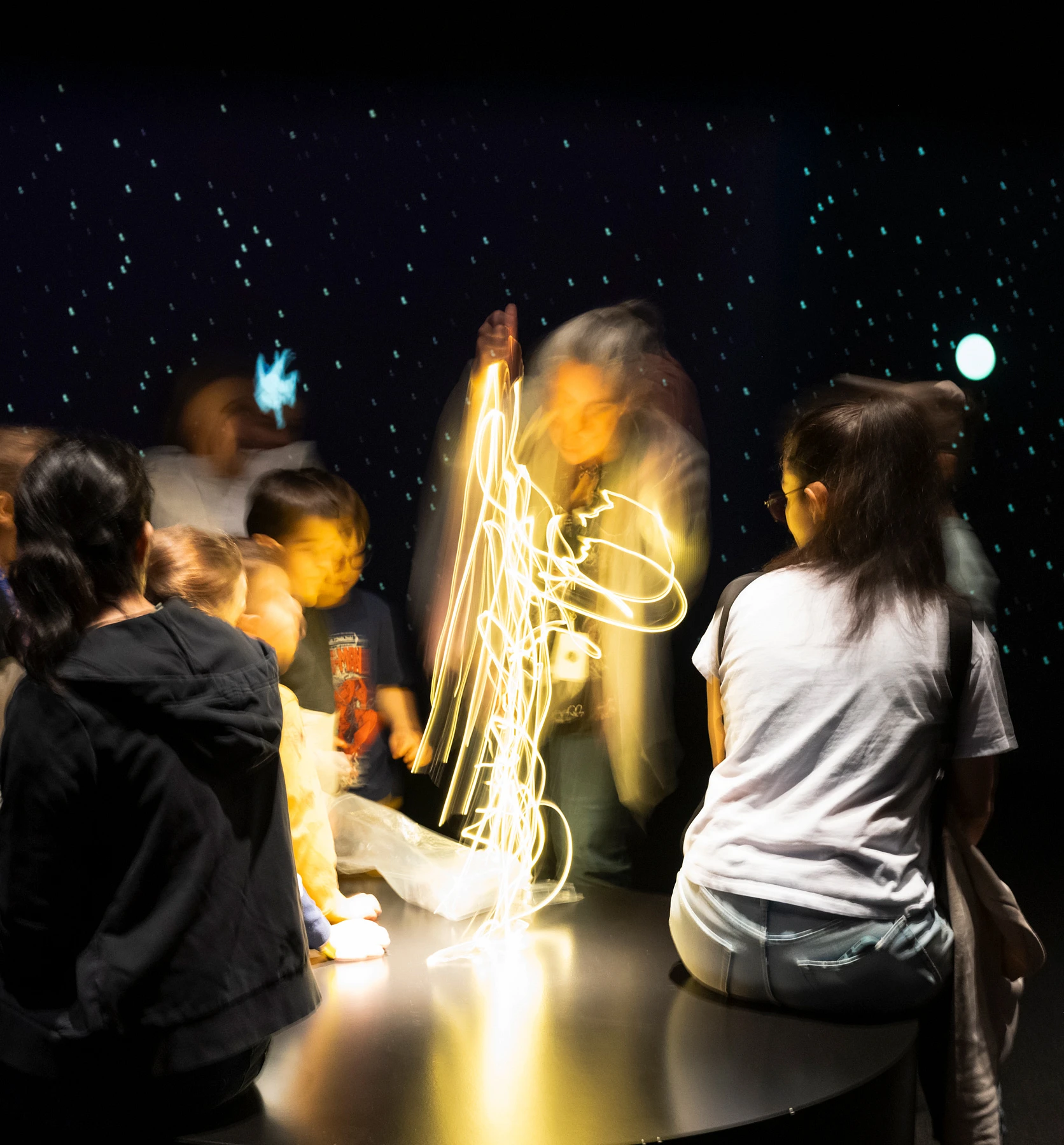 Groupe d'enfants assis sur le sol, autour d'un faisceau lumineux durant une activité du Musée national des beaux-arts du Québec.