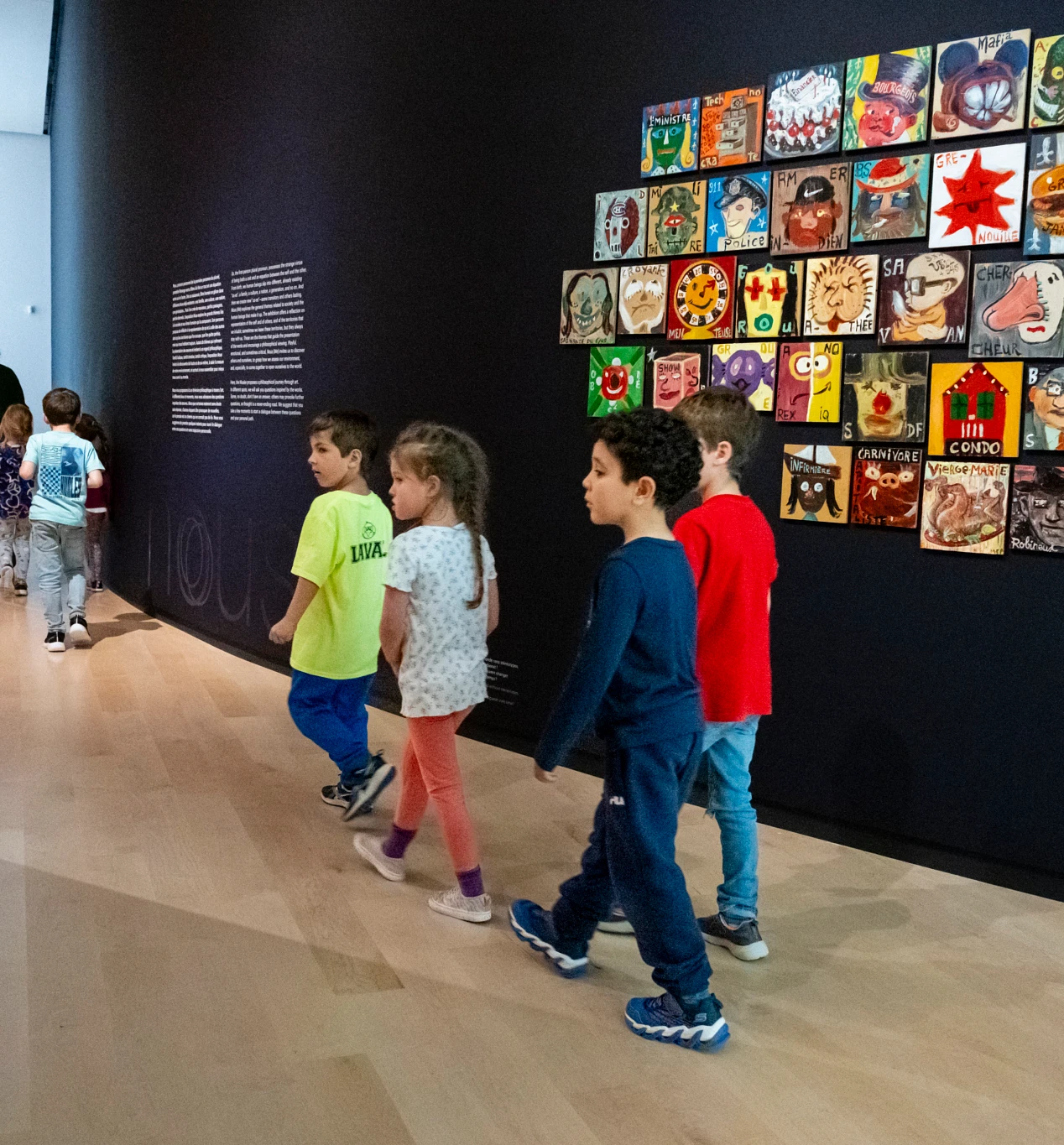 Un groupe scolaire de niveau primaire en visite dans l’exposition Nous. À gauche : Marie-Claude Pratte, Portraits de société, 1999-2000 (CP.2020.14) © Marie-Claude Pratte