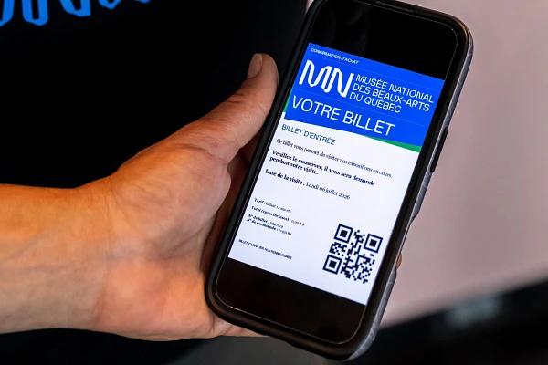 Un visiteur présente son billet à l'entrée d'une salle d'exposition