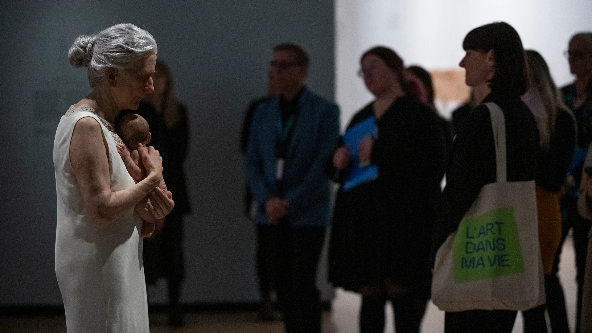 Un groupe devant l'oeuvre Femme et enfant de Sam Jinks