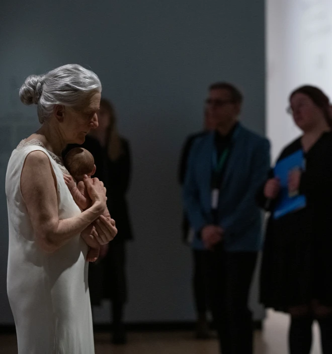 Un groupe devant l'oeuvre Femme et enfant de Sam Jinks