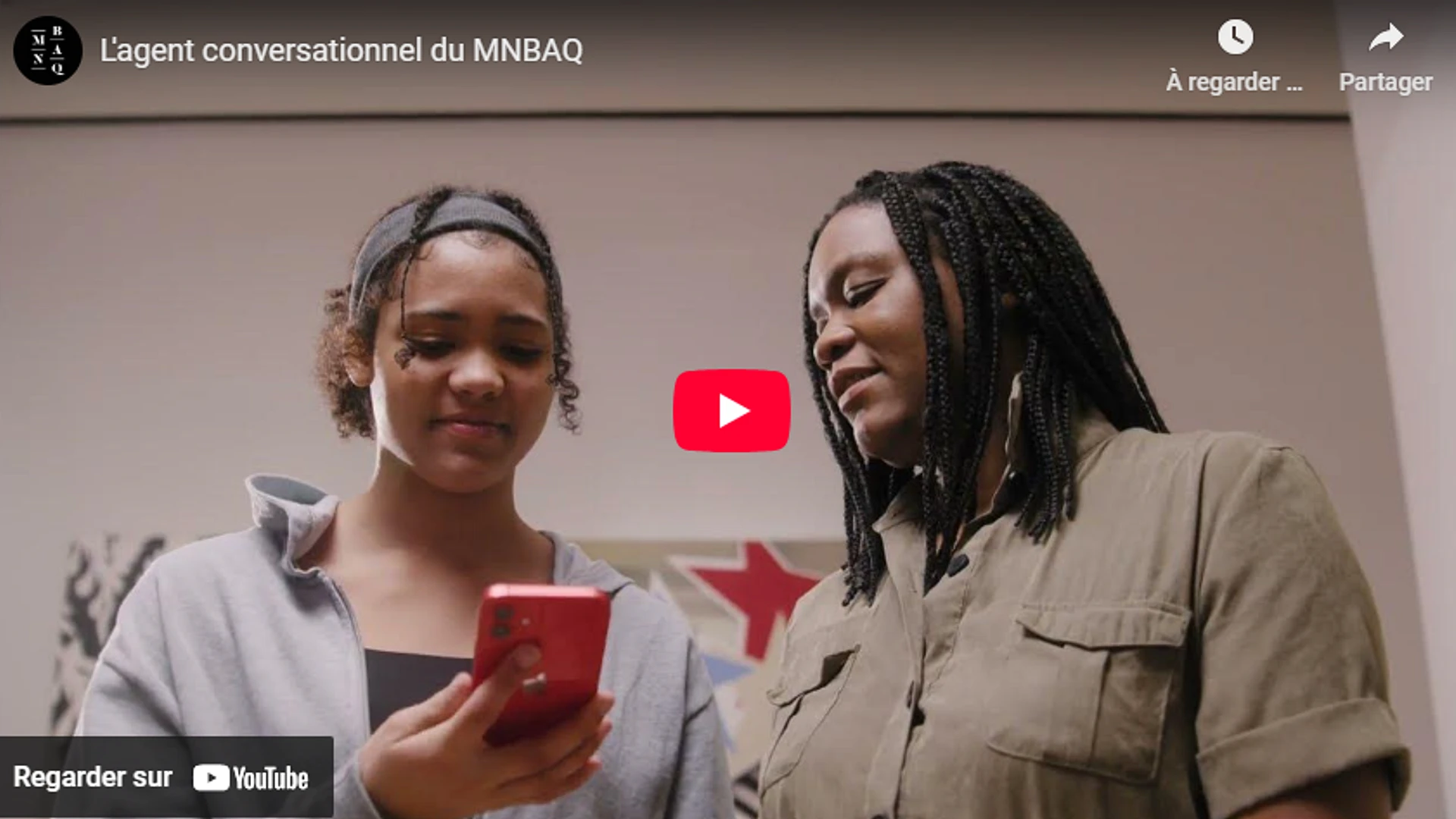 Capture écran d'un vidéo Youtube présentant deux femmes regardant un cellulaire.