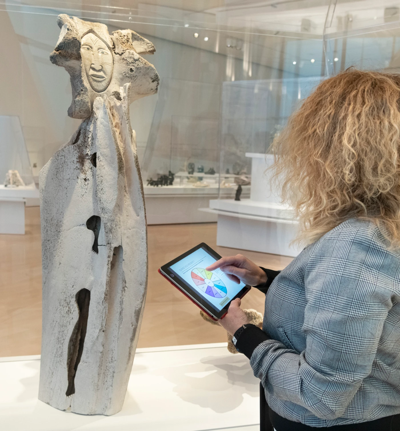 Femme devant une œuvre La Maternité de Manasie Aikpaliapik avec une tablette pour le projet Art et émotions